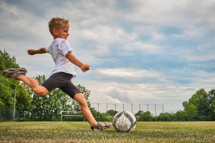 Junge schießt auf Bolzplatz einen Ball