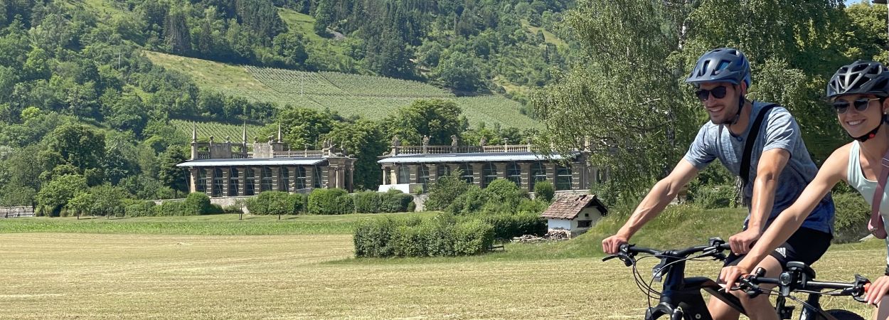 Zwei Radfahrer im Vordergrund und die Orangerie im Hintergrund