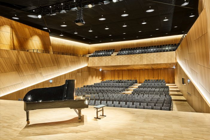 bestuhlter Konzertsaal mit Blick von der Bühne, Flügel